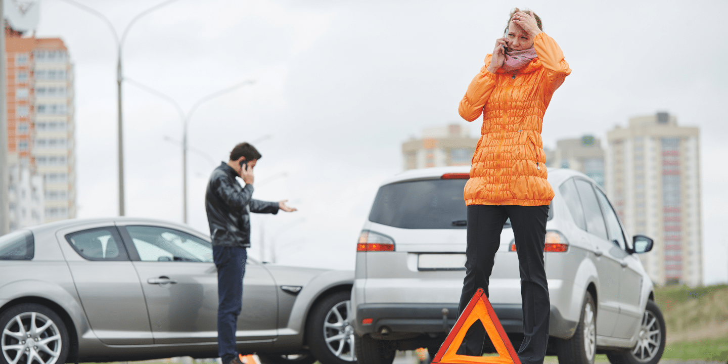 An accident on the highway involving two vehicles with a man and a woman standing outside their cars and making calls with their phones