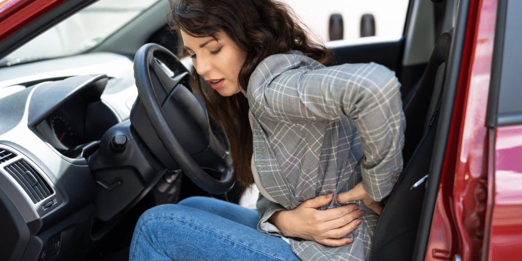 A lady touching the lower part of her back and feeling pain after an accident